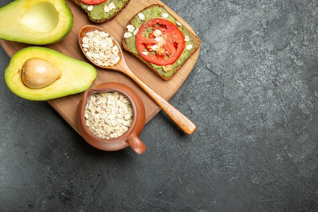 Bovenaanzicht heerlijke sandwiches met avocado en rode tomaten op de grijze achtergrond lunch snack maaltijd hamburger sandwich