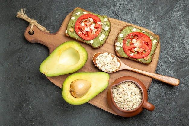 Bovenaanzicht heerlijke sandwiches met avocado en rode tomaten op het grijze oppervlak snack maaltijd hamburger sandwich brood