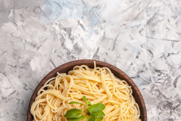 Bovenaanzicht heerlijke spaghetti met groen blad op witte tafelschotel maaltijd deeg pasta