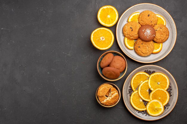 Bovenaanzicht heerlijke suikerkoekjes met vers gesneden sinaasappels op de donkere achtergrond suikerkoekje zoete koekjes fruitcake fruit