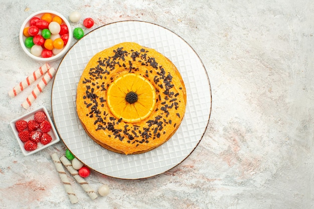 Bovenaanzicht heerlijke taart met kleurrijke snoepjes op witte oppervlakte taart biscuit zoete cake dessert regenboog