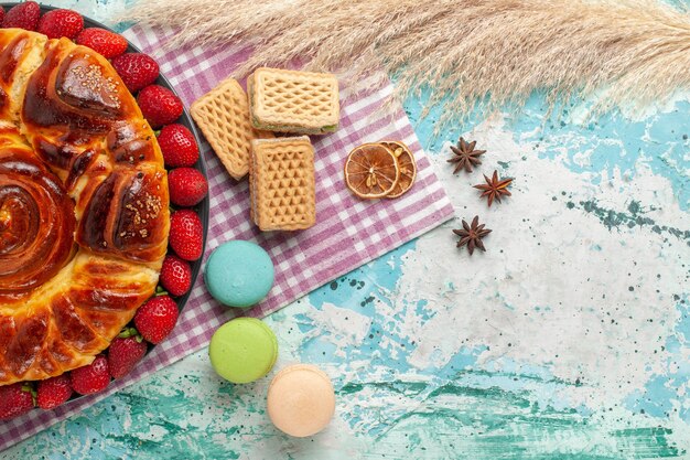 Bovenaanzicht heerlijke taart met macaronswafels en verse rode aardbeien op blauwe ondergrond