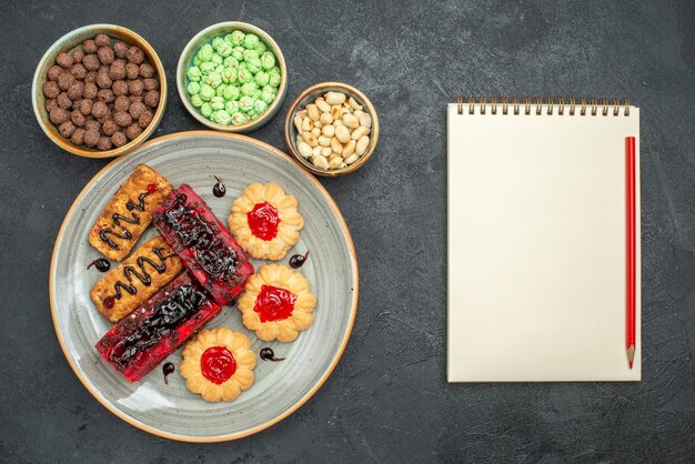 Bovenaanzicht heerlijke taarten fruitige snoepjes met koekjes en noten op de donkere achtergrond suikerkoekje biscuit cake zoete taart