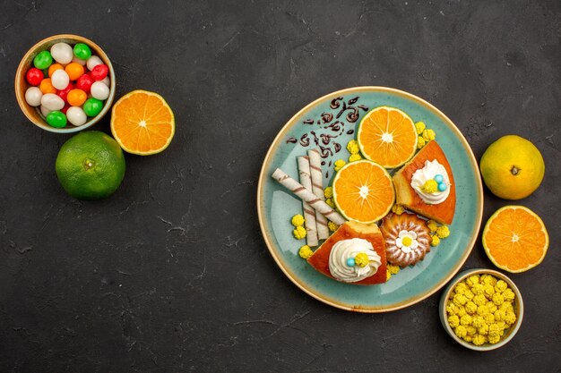 Bovenaanzicht heerlijke taartschijfjes met pijpkoekjes en vers gesneden mandarijnen op donkere bureau fruittaart taart zoete biscuit