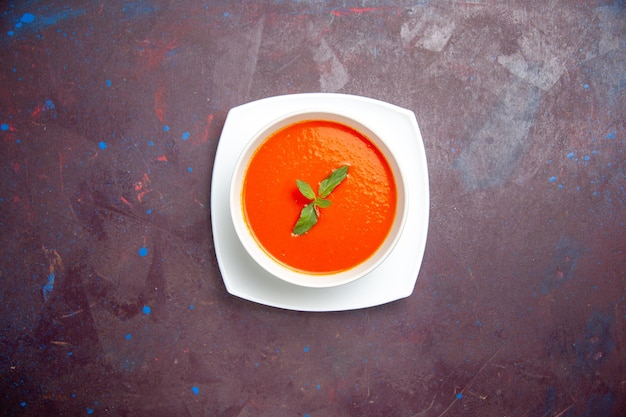 Bovenaanzicht heerlijke tomatensoep smakelijke schotel met enkel blad binnen plaat op een donkere achtergrond schotel saus tomaat kleur diner soep