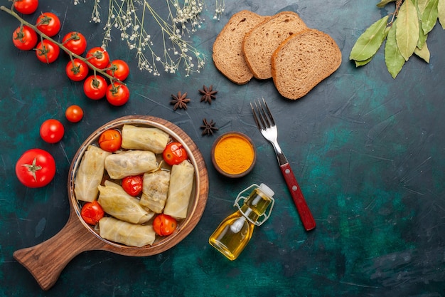 Bovenaanzicht heerlijke vleesmaaltijd gerold in kool met oliebrood en verse tomaten op donkerblauw bureau vlees eten diner calorieën groenten schotel koken