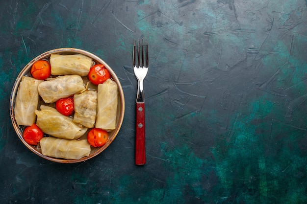 Bovenaanzicht heerlijke vleesmaaltijd gerold in kool met tomaten op het donkerblauwe bureau vlees eten diner calorieën groente koken