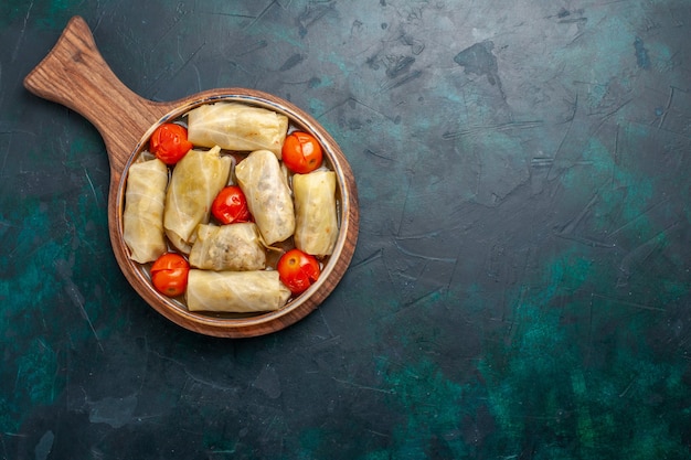 Bovenaanzicht heerlijke vleesmaaltijd gerold in kool met tomaten op het donkerblauwe bureau vlees eten diner calorieën groenteschotel koken