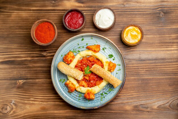 Bovenaanzicht heerlijke vleesplakken met aardappelpuree en smaakmakers op de houten bureauschotel vleesmaaltijd aardappelbrood eten