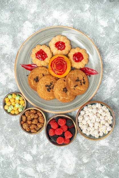 Bovenaanzicht heerlijke zandkoekjes met koekjes en snoepjes op lichte witte achtergrondkoekje, zoete suikercake, theekoekje