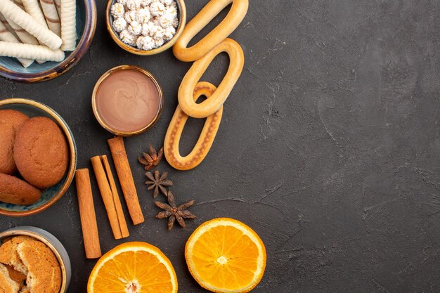 Bovenaanzicht heerlijke zandkoekjes met vers gesneden sinaasappels op donkere achtergrondkoekjes, suikerfruit, zoete citruskoekjes