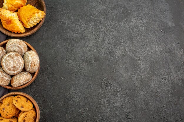 Bovenaanzicht heerlijke zoete taarten met koekjes op donkere oppervlakte zoete taart