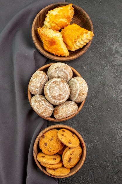 Bovenaanzicht heerlijke zoete taarten met koekjes op donkere oppervlakte zoete taart