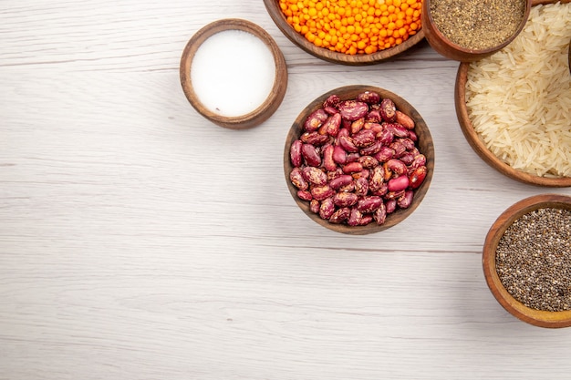 Bovenaanzicht houten kommen met rijst zwarte peper zout bonen op grijze tafel