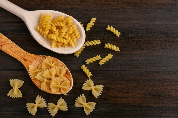 Bovenaanzicht houten lepels met rauwe pasta op een houten tafel