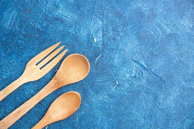 Bovenaanzicht houten mes vork lepel op blauwe tafel vrije plaats