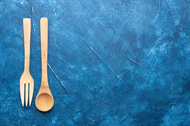 Bovenaanzicht houten vork lepel op blauwe tafel met kopie plaats