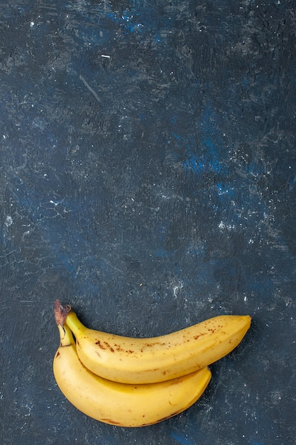 Bovenaanzicht in de verte gele bananen paar bessen op donker bureau, fruit bes vers zacht voedsel gezondheid vitamine zoet