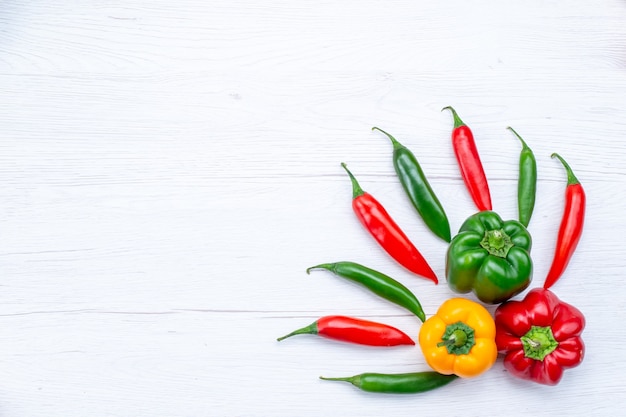 Bovenaanzicht in de verte kleurrijke paprika's met pittige paprika's op wit bureau, plantaardig kruid warm voedsel maaltijd ingrediënt product