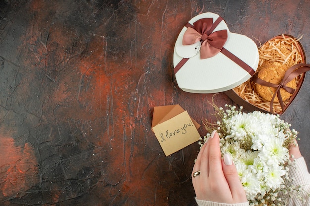 Bovenaanzicht jonge vrouw krijgt huwelijksaanzoek met bloemen op donkere achtergrond vakantiegevoel paar cadeau kleur liefde vrije ruimte Gratis Foto
