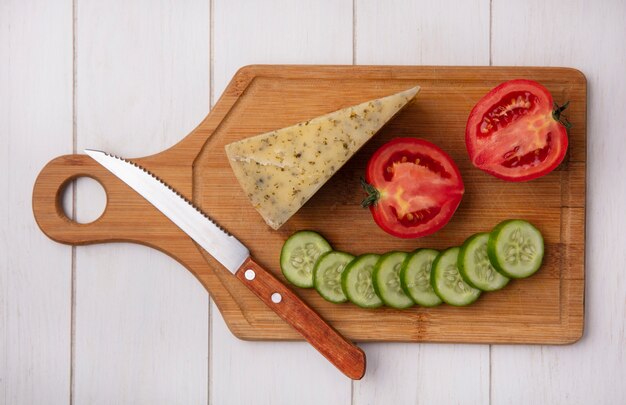 Bovenaanzicht kaas met tomaten komkommer en mes op een stand op een witte achtergrond