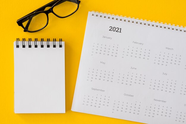 Bovenaanzicht kalender met notitieblok en bril