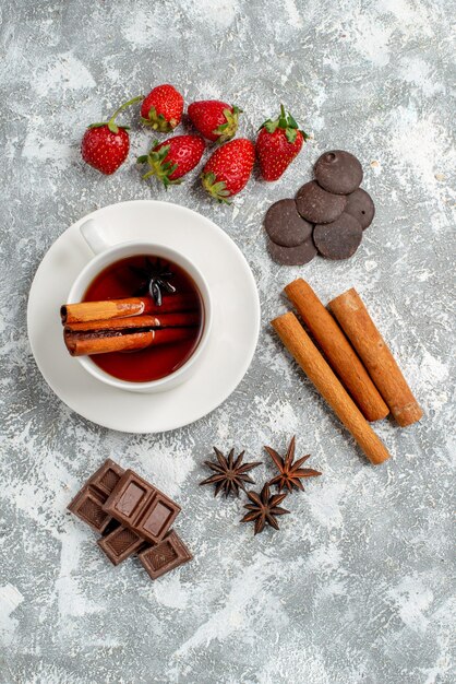 Bovenaanzicht kaneel anijszaad thee en wat aardbeien chocolaatjes kaneel anijs zaden aan de linkerkant van de tafel