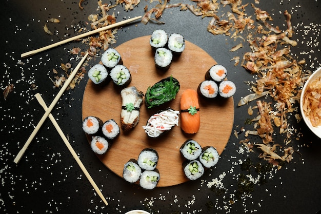 Bovenaanzicht kappa maki rolt met shake maki en sashimi sushi met stokjes op een standaard