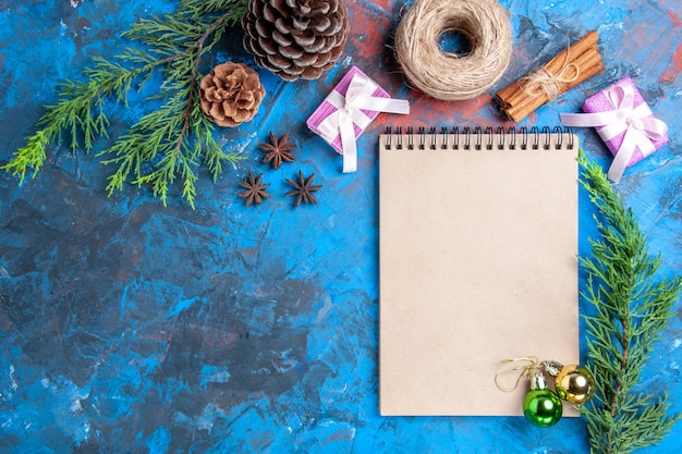 Bovenaanzicht kerstballen op een notebook pijnboomtakken kaneelstokjes anijs gedroogde citroen plakjes op blauwe oppervlak vrije plaats