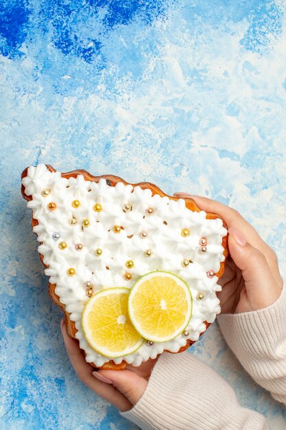 Bovenaanzicht kerstboom cake in vrouwelijke hand op blauwe tafel vrije ruimte