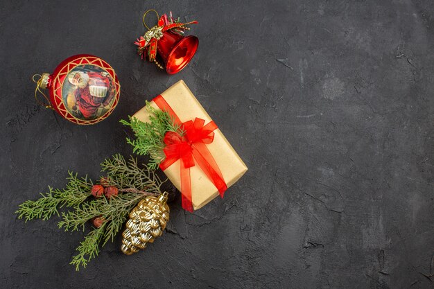 Bovenaanzicht kerstcadeau in bruin papier gebonden met rood lint kerstboom ornamenten op donkere achtergrond kopie ruimte