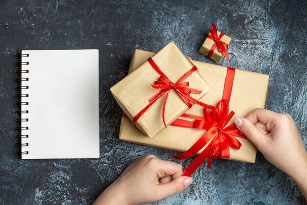 Gratis foto bovenaanzicht kerstcadeautjes vastgebonden met rode strikken op de licht-donkere achtergrond