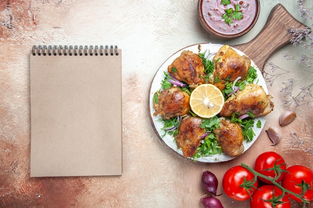 Bovenaanzicht kip kip met kruiden citroen op het bord tomaten saus room notebook