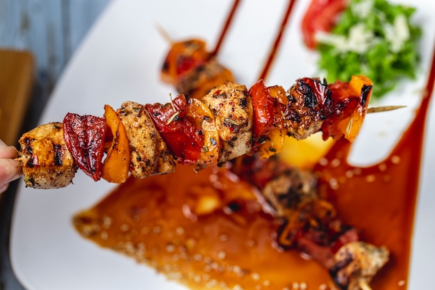 Bovenaanzicht kipspiesjes gegrilde kipfilet met rode en gele pepers kruiden saus en sesamzaadjes op een bord