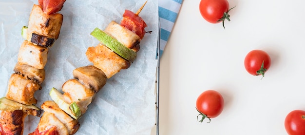 Bovenaanzicht kipspiesjes op perkamentpapier met tomaten