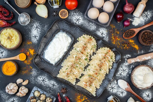 Bovenaanzicht kleine gekookte dumplings met verschillende ingrediënten op donkere achtergrond schotel diner kleur deeg crème maaltijd