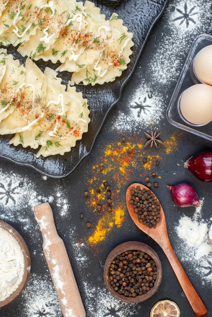 Bovenaanzicht kleine gekookte dumplings met verschillende ingrediënten op het donkere oppervlak