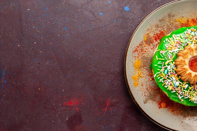 Bovenaanzicht kleine heerlijke cake met groene room op het donkere oppervlak