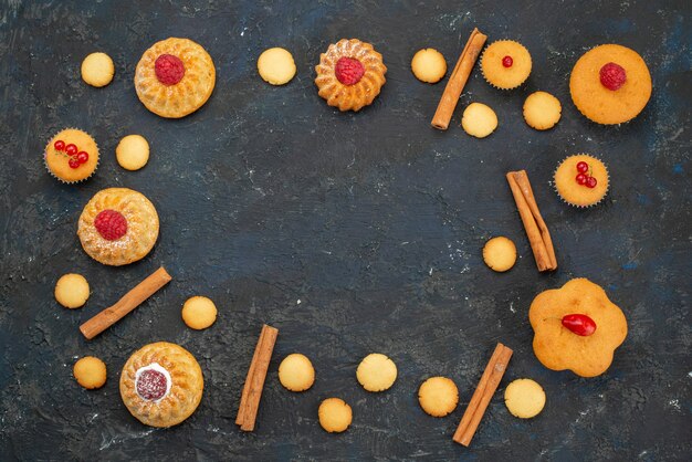 Bovenaanzicht kleine lekkere cakes met roomkoekjes kaneel op het donkere bureau zoete koektaart dessert fruitbes