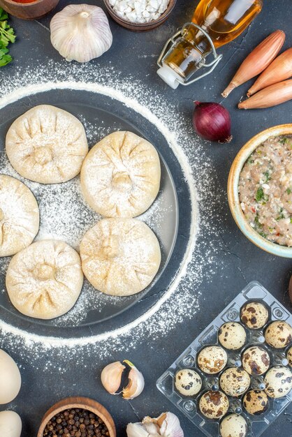 Bovenaanzicht kleine rauwe dumplings met verschillende ingrediënten op de grijze achtergrond voedsel taart taart koken smakelijk vlees deeg kleur meel bakken