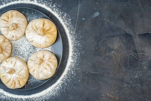 Gratis foto bovenaanzicht kleine rauwe dumplings op grijze achtergrond kleur voedsel taart meel bakken vlees deeg ei smakelijke vrije plaats voor tekst