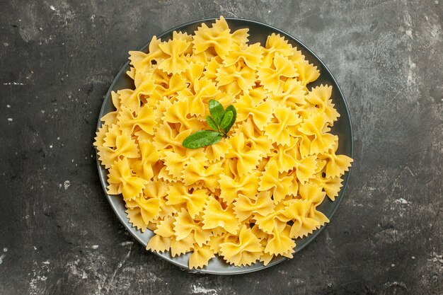 Bovenaanzicht kleine rauwe pasta in plaat op donkergrijze achtergrond