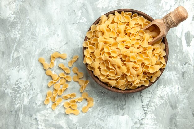 Bovenaanzicht kleine rauwe pasta in plaat op lichte achtergrond