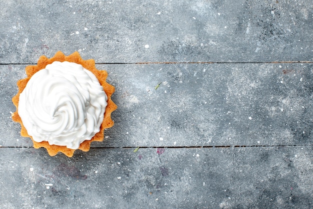 Bovenaanzicht kleine romige cake heerlijk gebakken geïsoleerd op de grijze achtergrond cake koekje zoete suiker