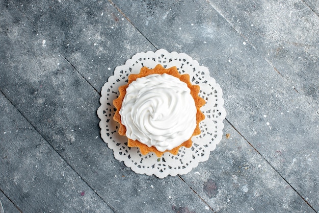 Bovenaanzicht kleine romige cake heerlijk gebakken geïsoleerd op de grijze lichte achtergrond cake biscuit suiker room bakken