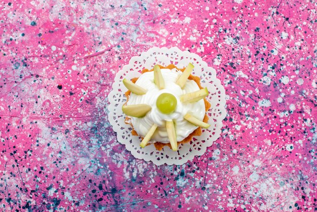 Bovenaanzicht kleine romige cake met gesneden fruit op de gekleurde achtergrond cake zoete suiker bakken kleurenfoto