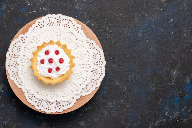 Gratis foto bovenaanzicht kleine romige cake met rood fruit op het donkere zoete oppervlak