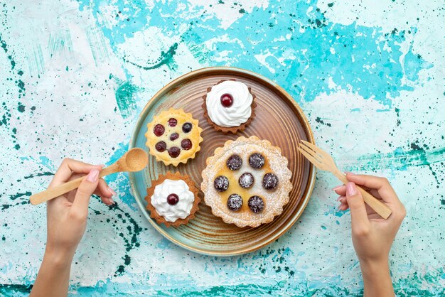 Bovenaanzicht kleine romige cakes met suikerpoeder fruit op de lichtblauwe achtergrond cakecrème bak zoet