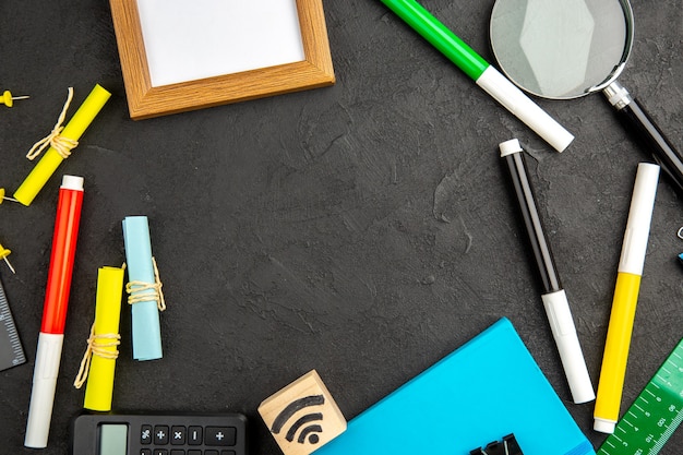 Bovenaanzicht kleurrijke potloden met fotolijst en rekenmachine op een donkere achtergrond schooltekening kleurenfoto