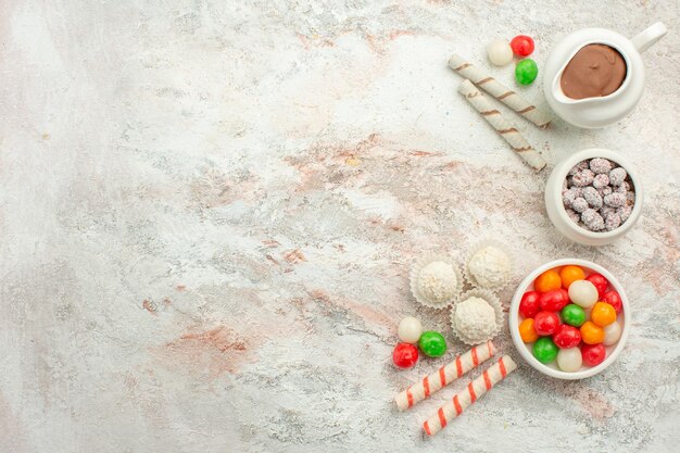 Bovenaanzicht kleurrijke snoepjes met koekjes op de lichte witte achtergrondkleur regenboog biscuit thee cake